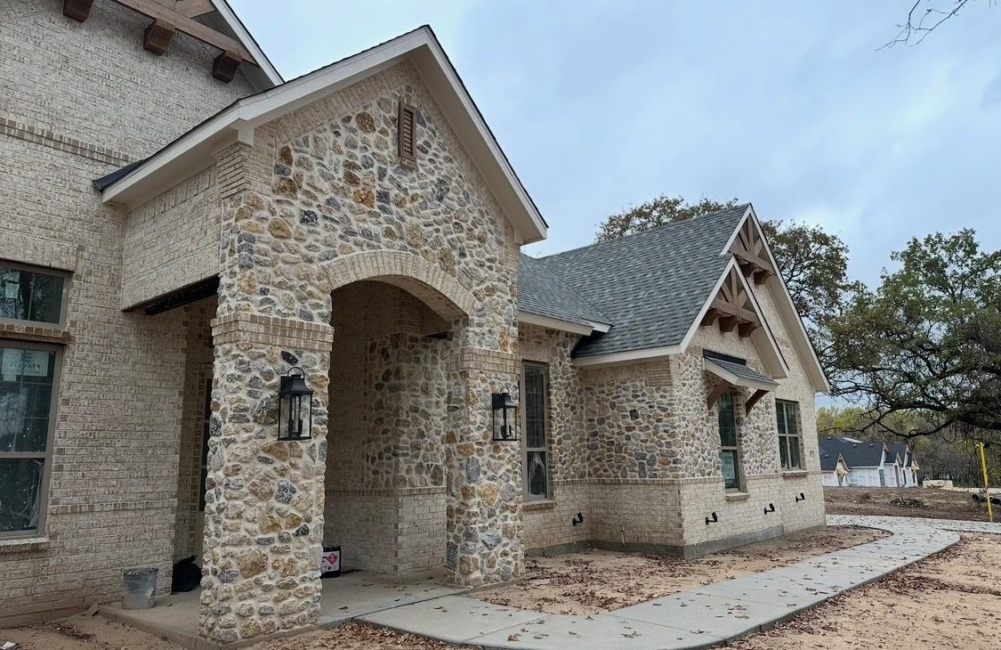 The stone entry arch and brick front seen from the walk, with stone columns at the porch